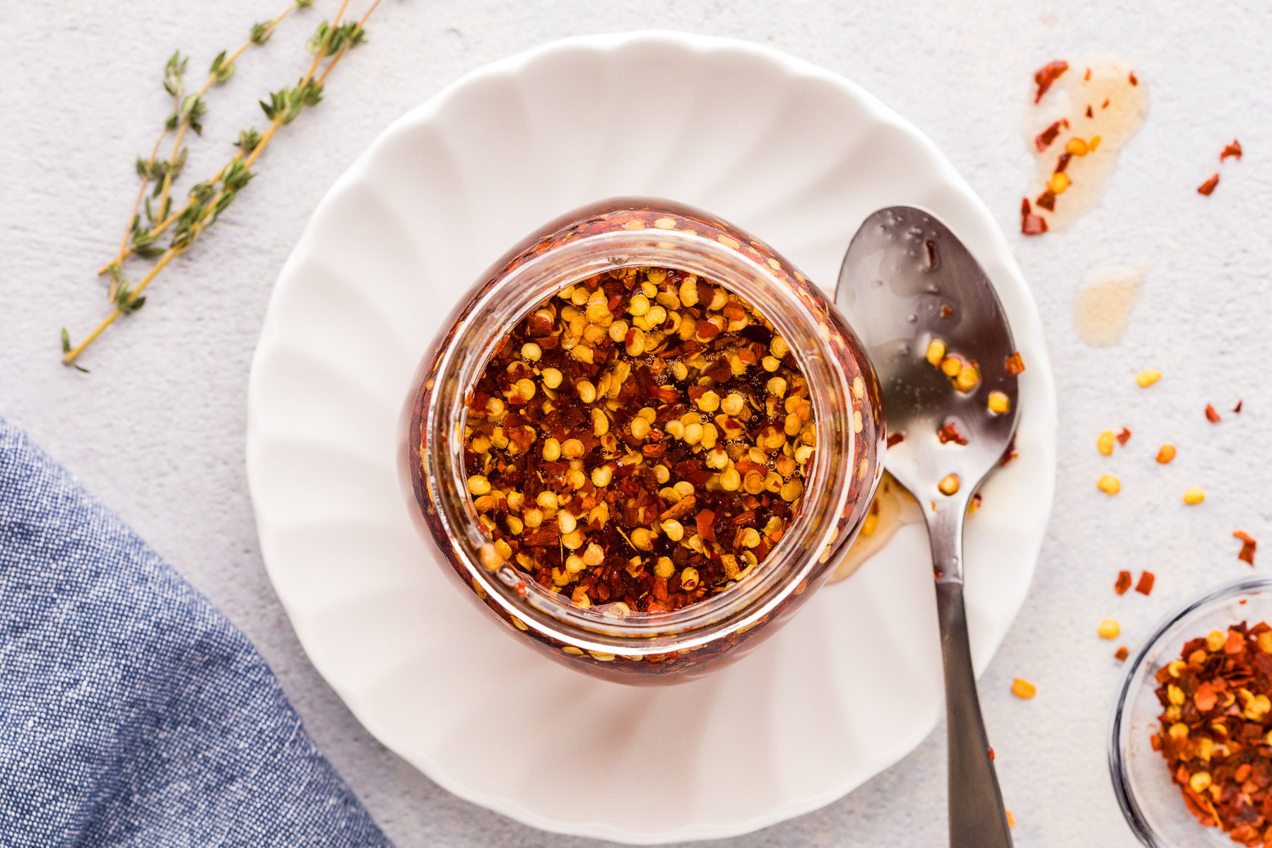 Hot honey in a jar on a white plate with spoon to serve.