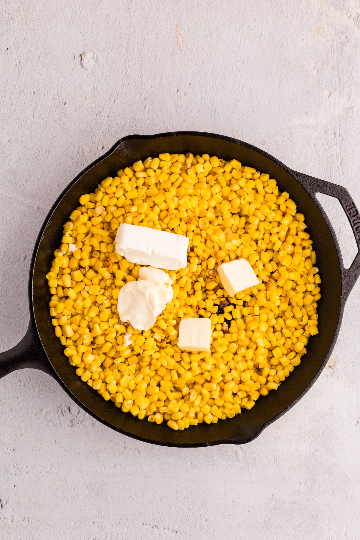 Cream cheese butter and mayonnaise added to charred corn in a cast iron skillet