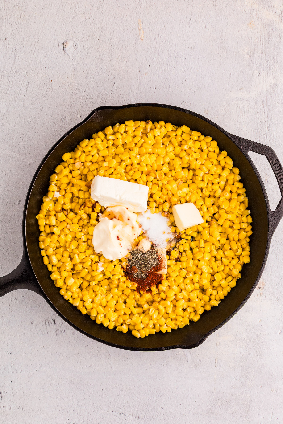 Hot honey salt paprika and pepper added to skillet corn with cream cheese and butter
