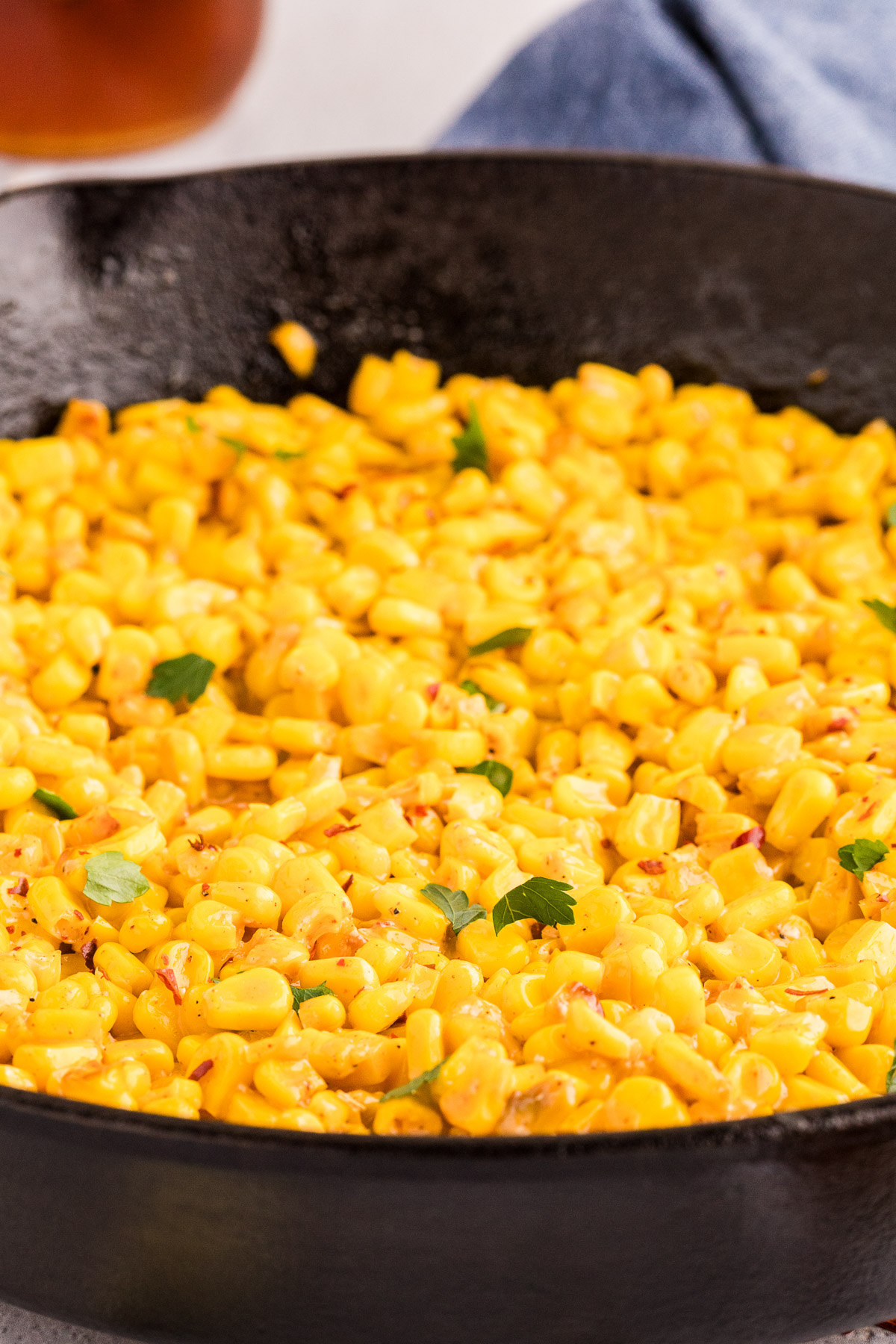 Hot honey butter skillet corn garnished with parsley and red pepper flakes in a cast iron skillet