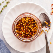 Hot honey in a jar on a white plate with spoon to serve.