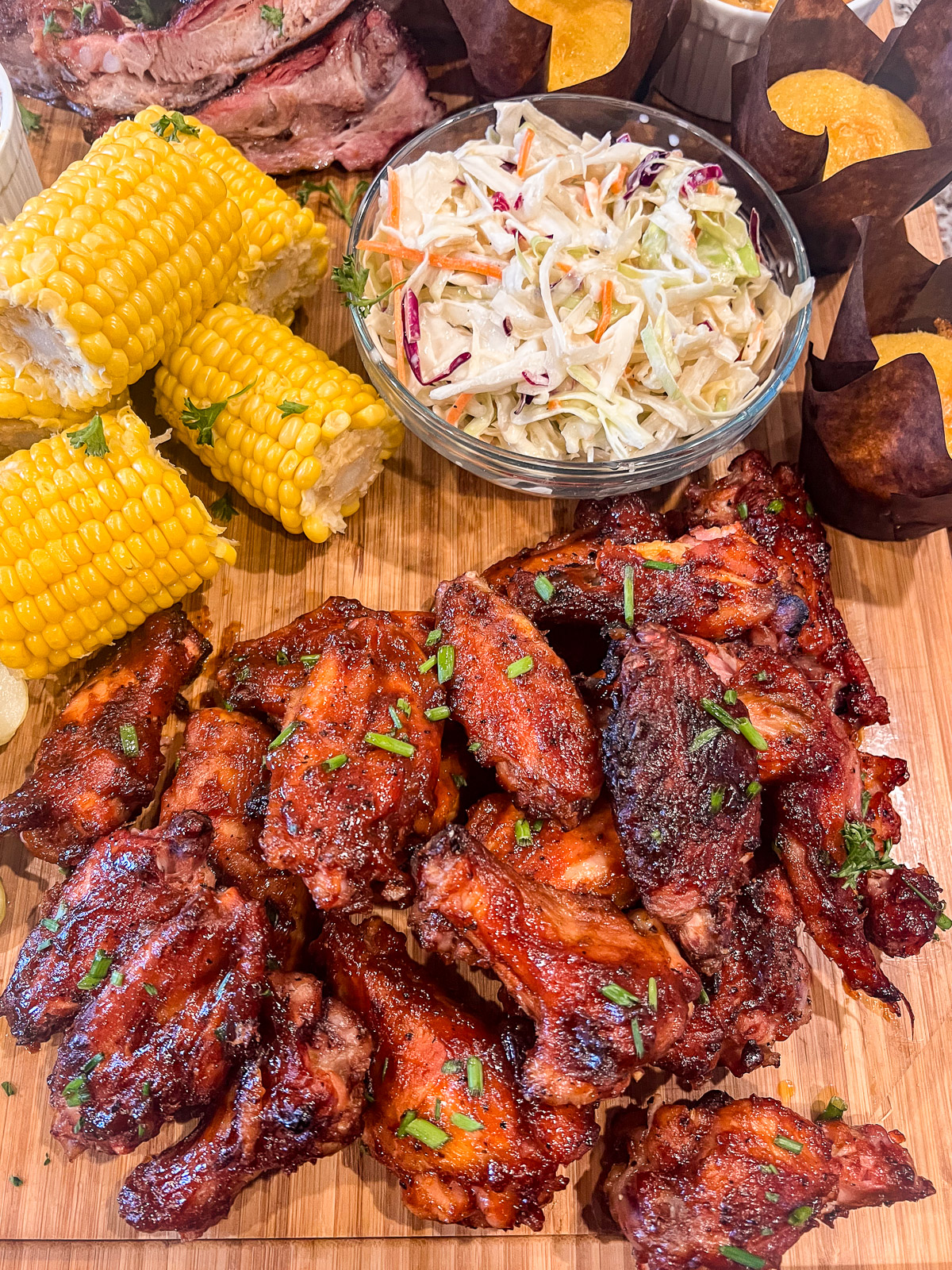 Smoked maple bourbon chicken wings on a platter with coleslaw and corn.