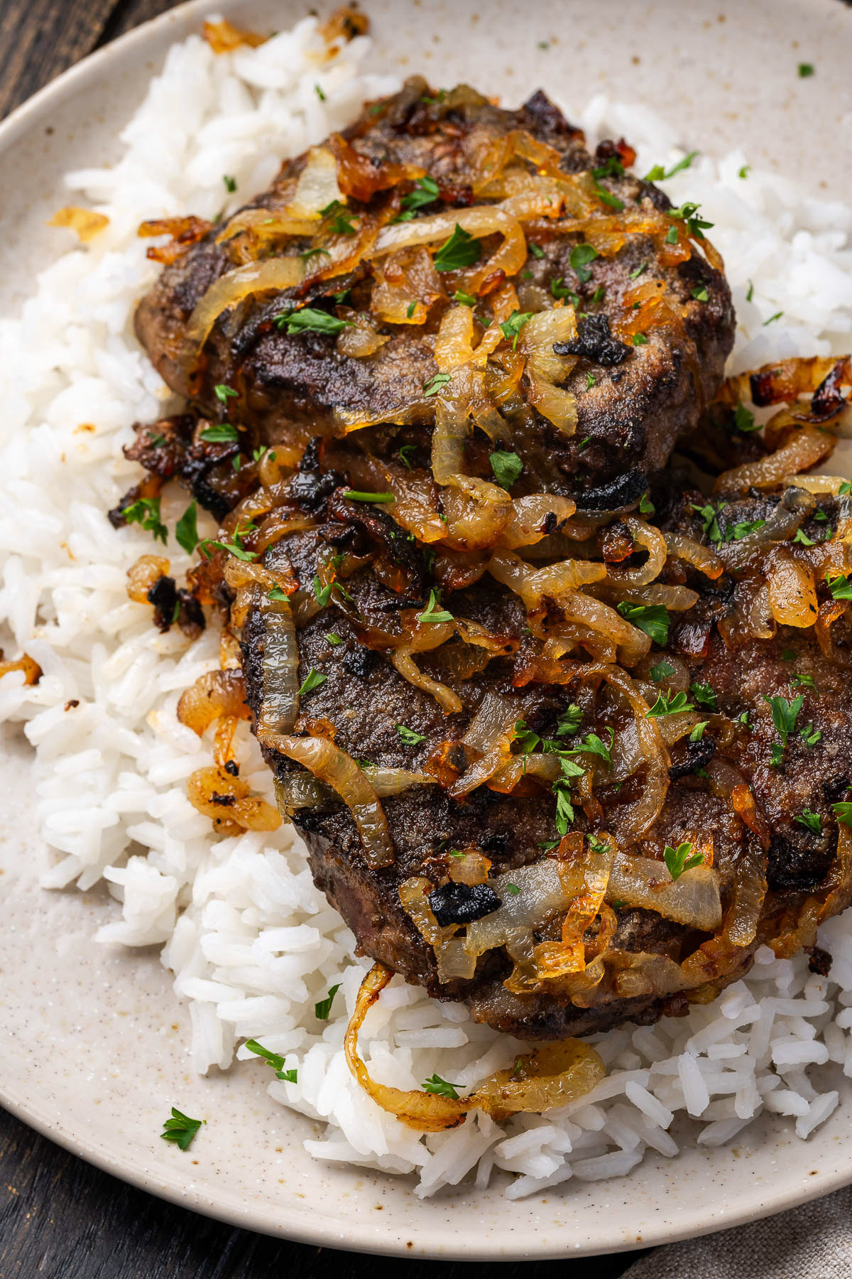 Liver and onions plated over white rice portrait view