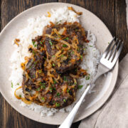 Liver and onions served over white rice on a plate with a fork