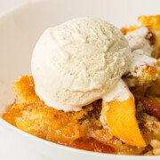 Peach Cobbler with ice cream in a white bowl.