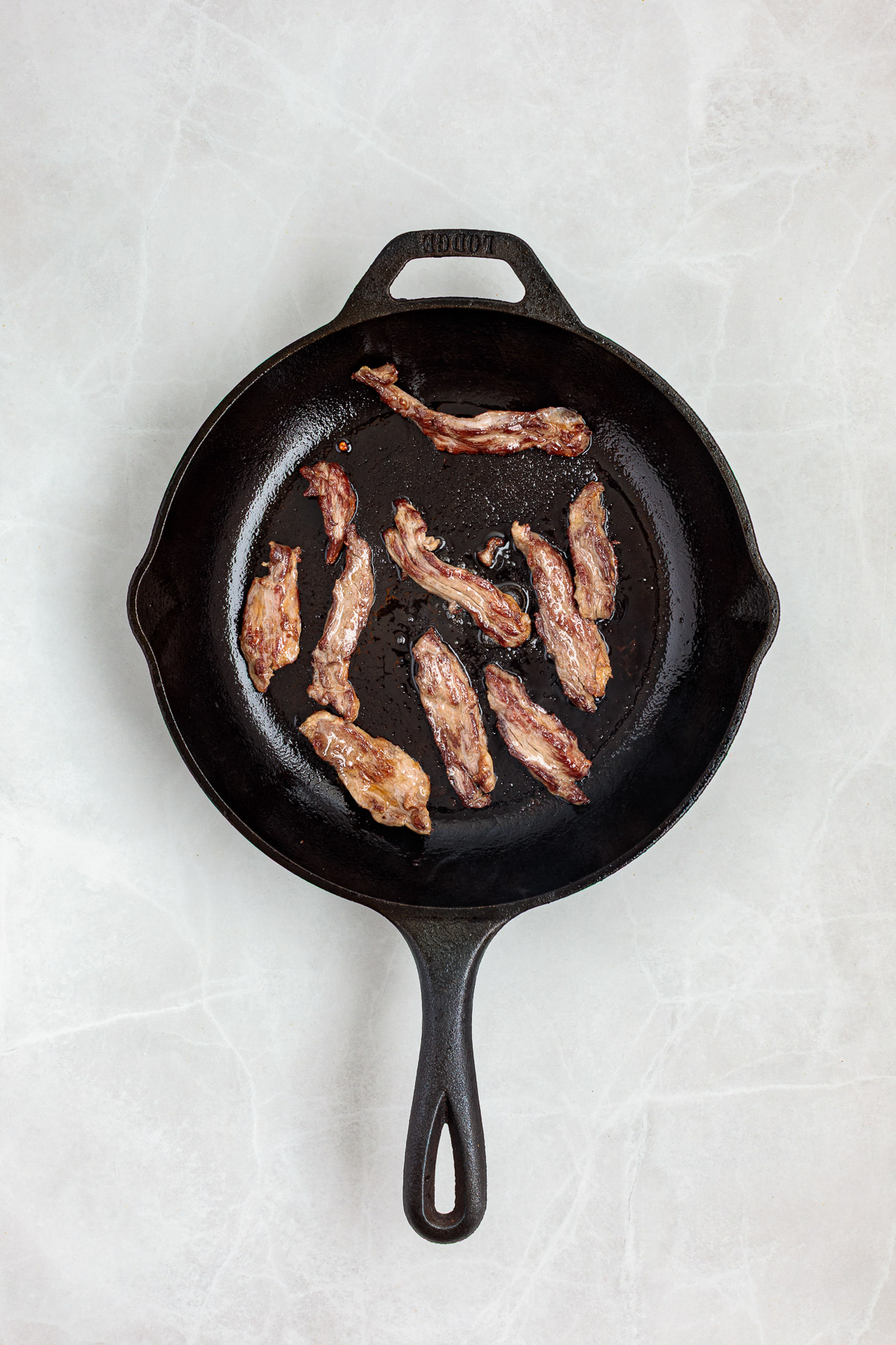Skirt steak browned in a cast iron skillet.