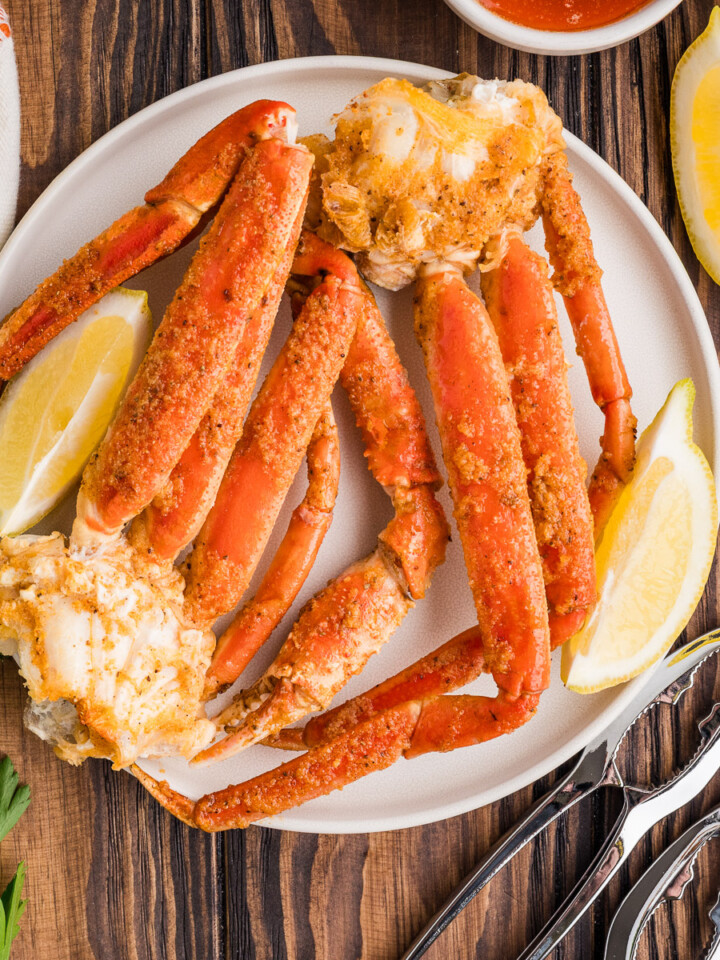 A plate of smoked crab legs with lemon wedges.
