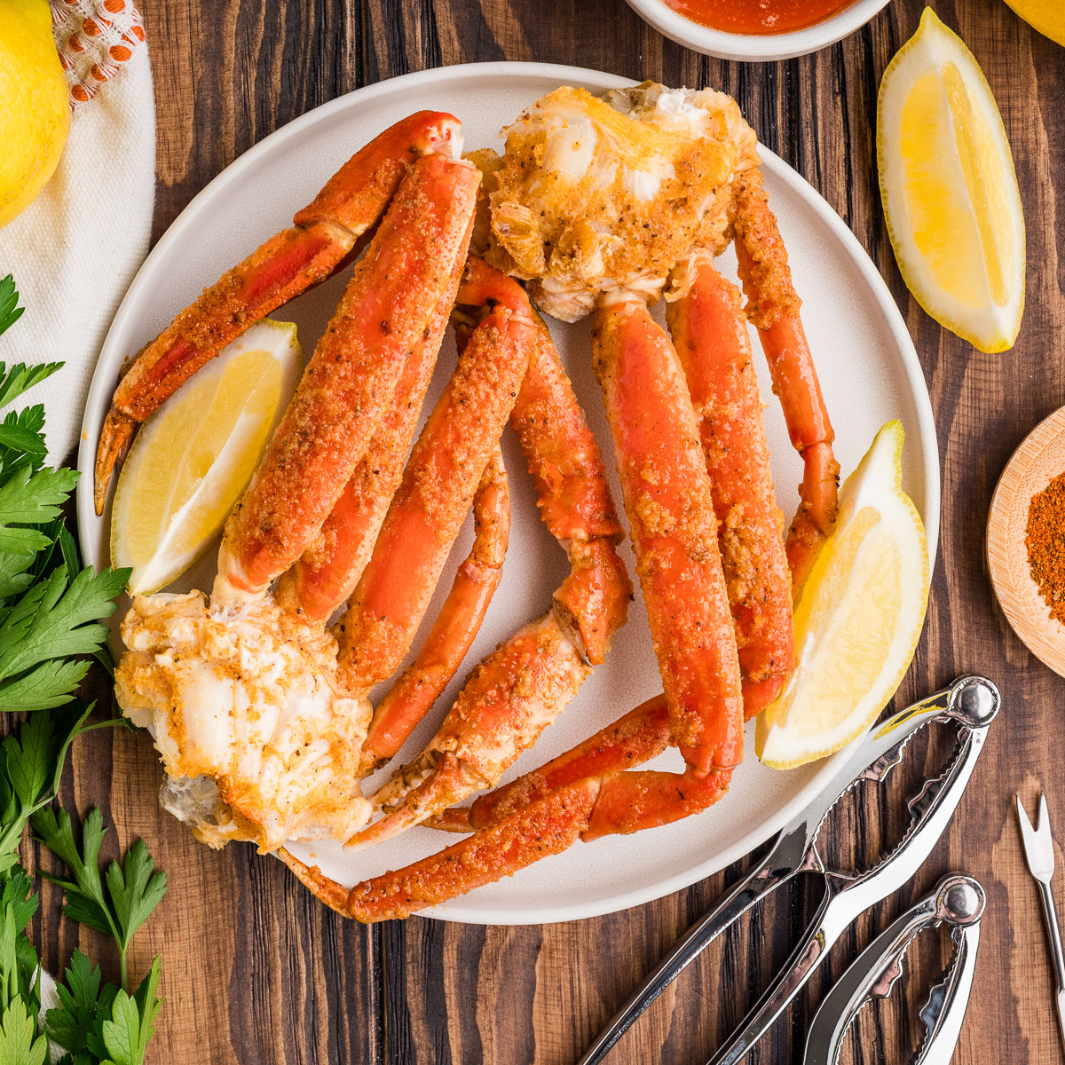 A plate of smoked crab legs with lemon wedges.