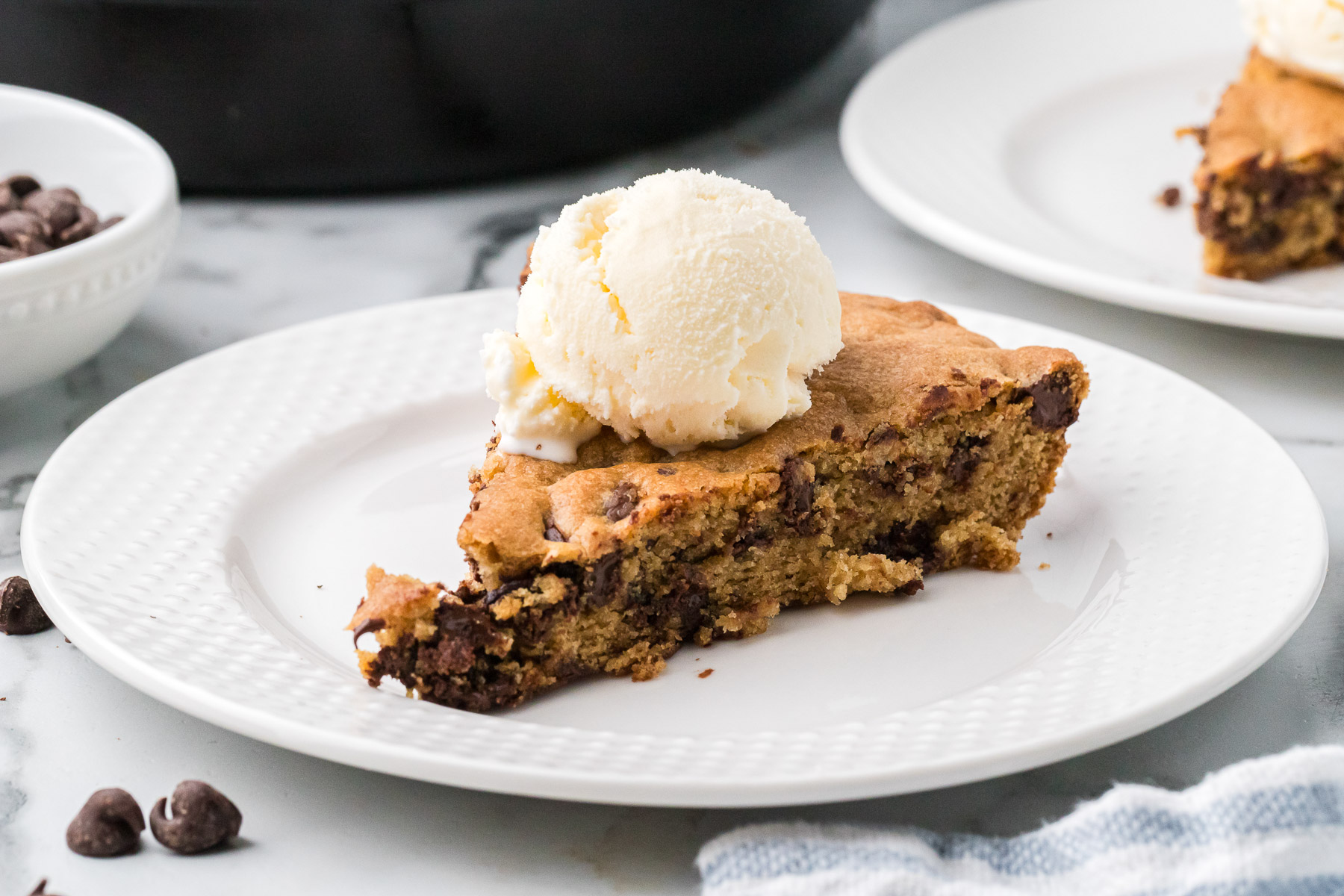 A slice of sourdough chocolate chip skillet cookie with vanilla ice cream.