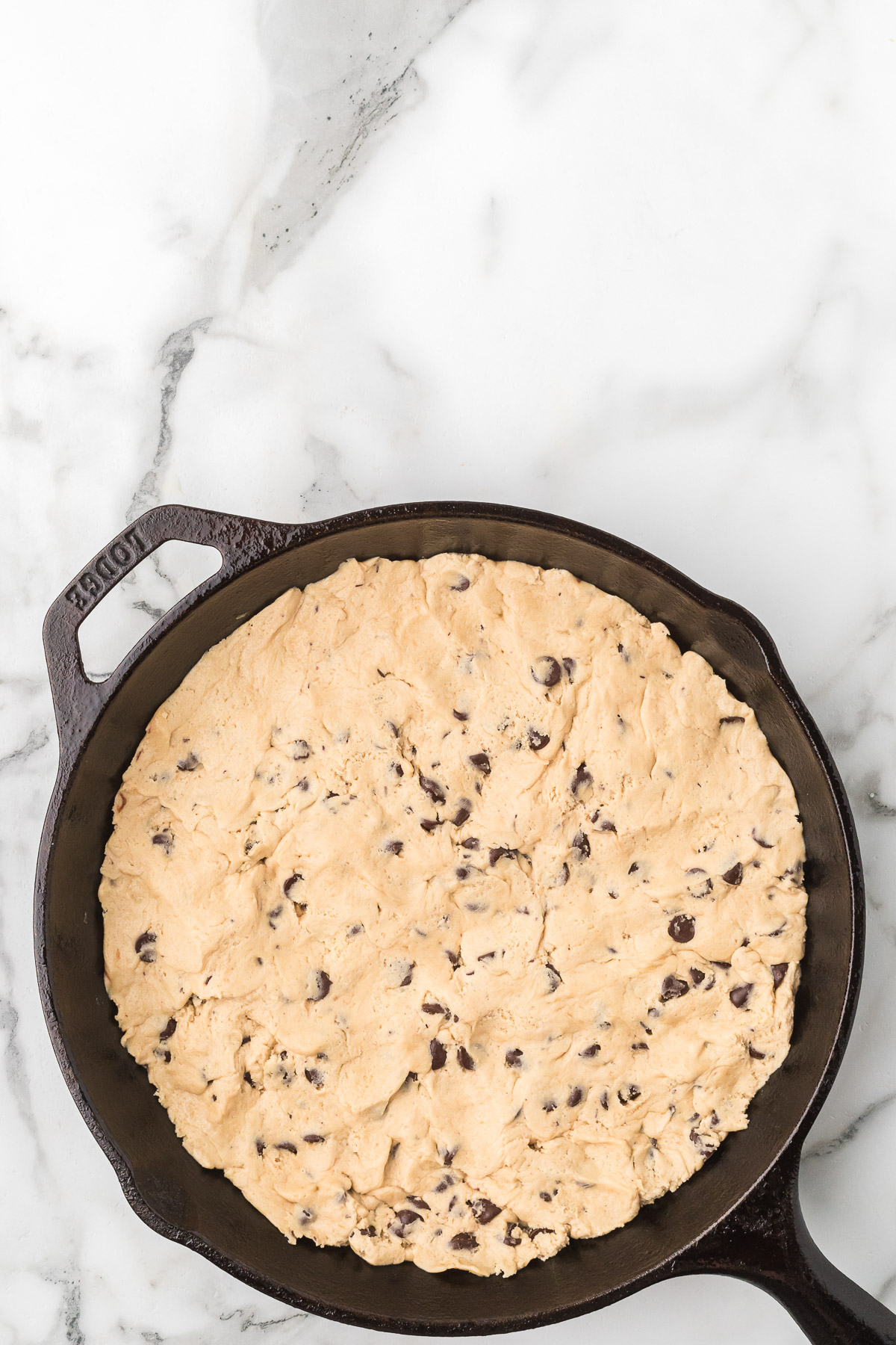 Sourdough chocolate chip cookie dough pressed into a cast iron skillet.