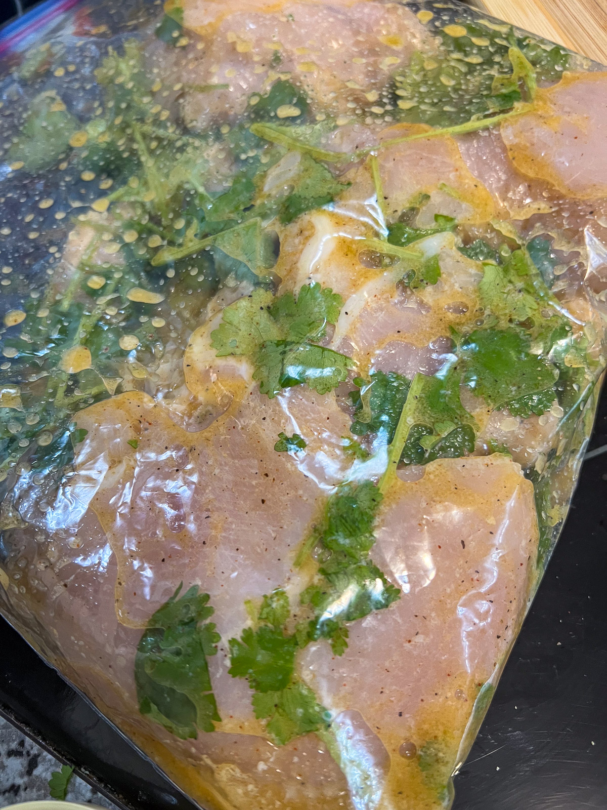 Chicken breasts marinating in tequila lime marinade with cilantro in a sealed bag