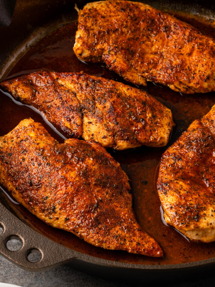 Cast iron skillet chicken breasts searing in a cast iron pan.