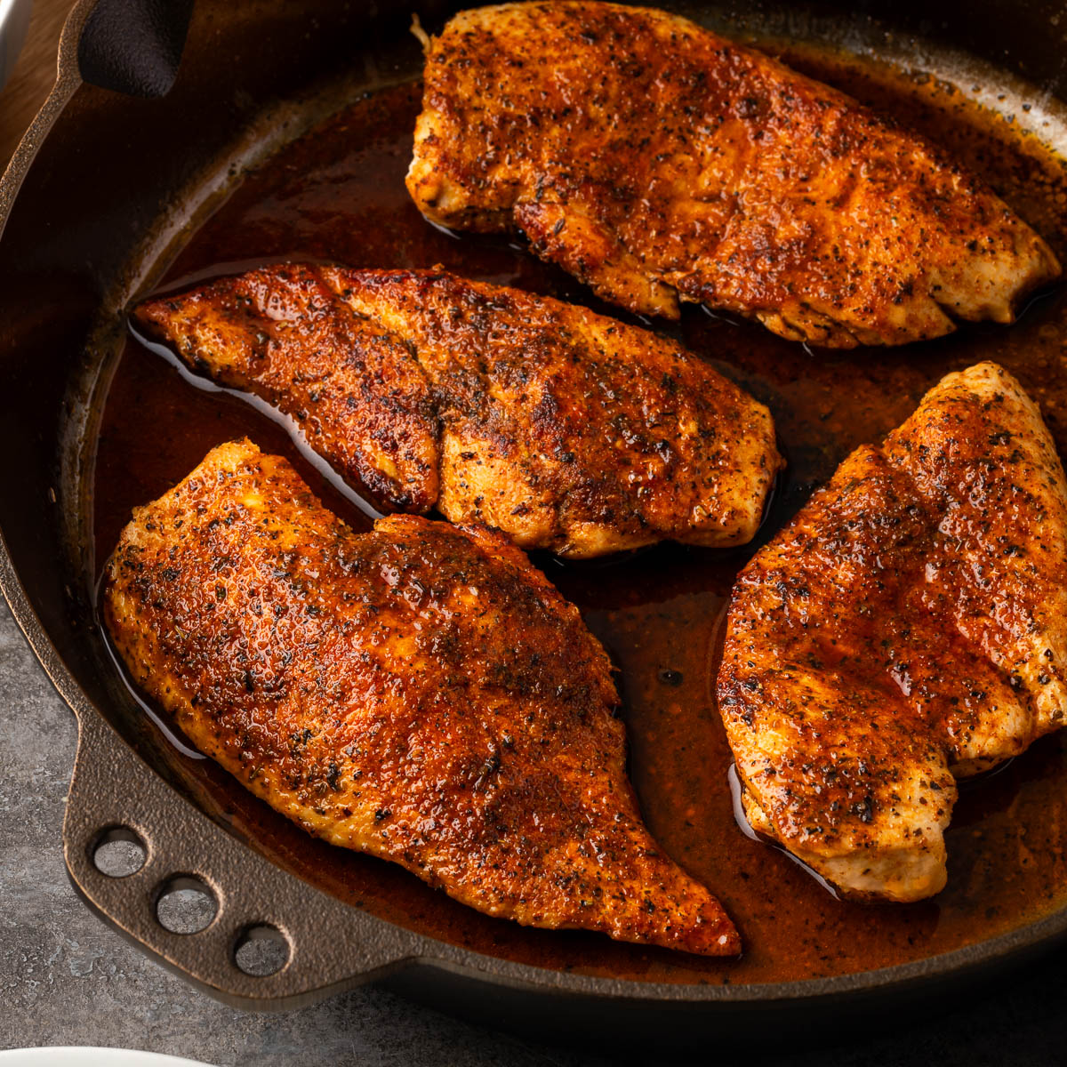 Cast iron skillet chicken breasts searing in a cast iron pan.