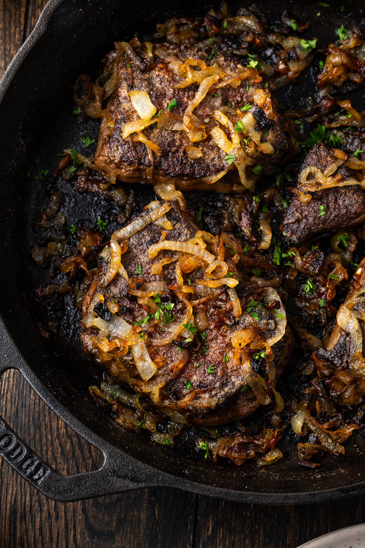 Old fashioned liver and onions in a cast iron skillet on a dark wood table