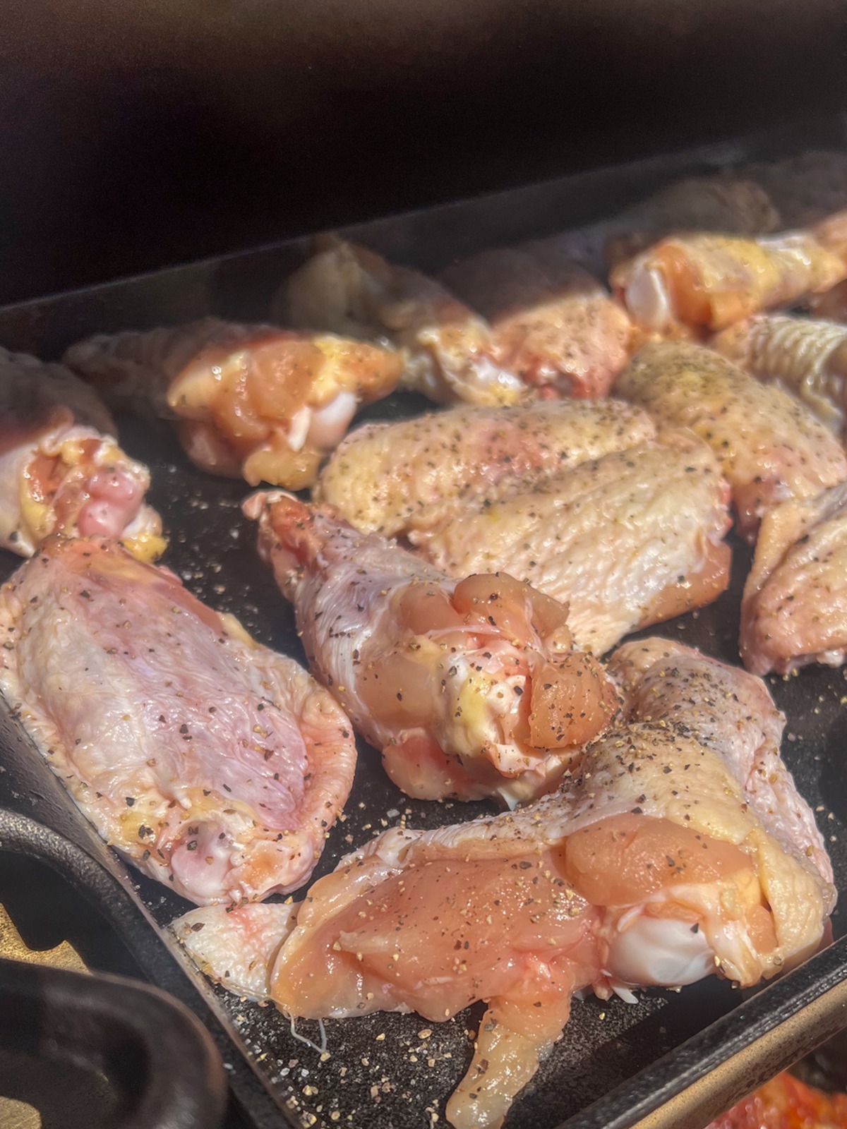 Chicken wings smoking on a pellet smoker grate before glazing.