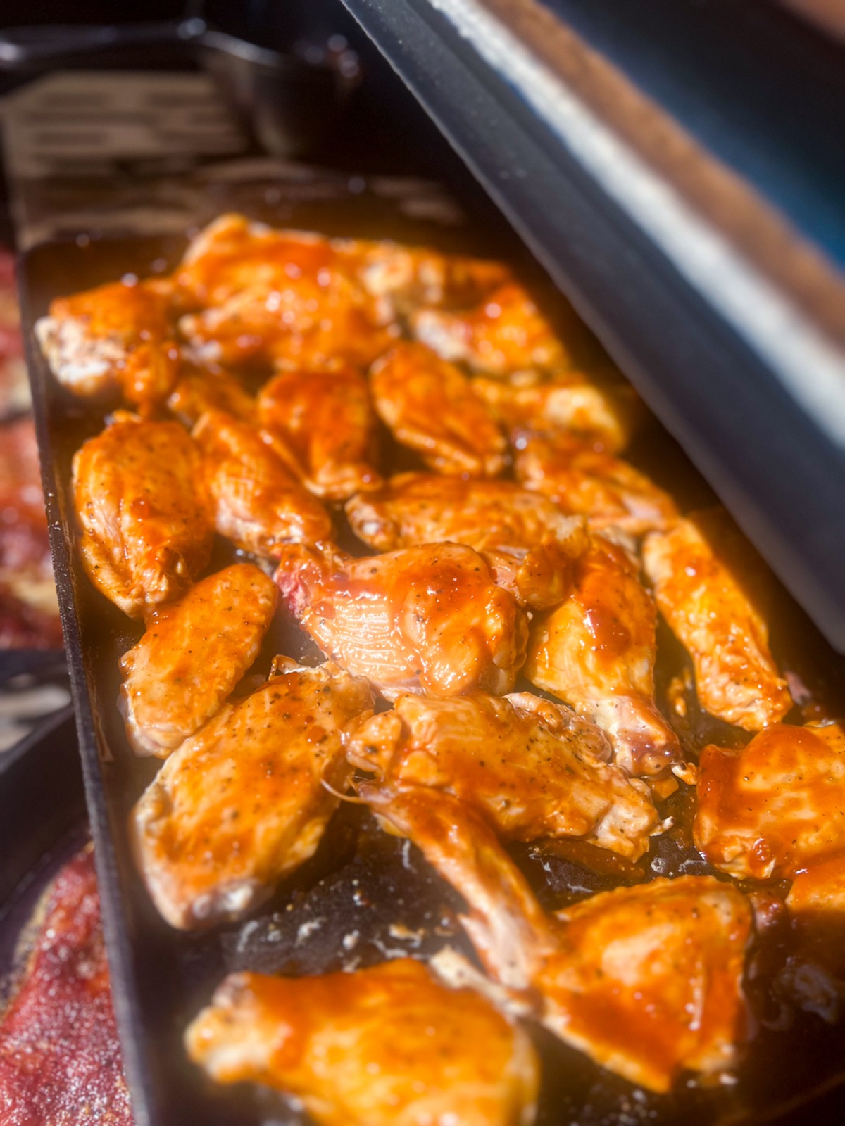 Smoked chicken wings tossed with sticky maple bourbon glaze in a cast iron skillet.