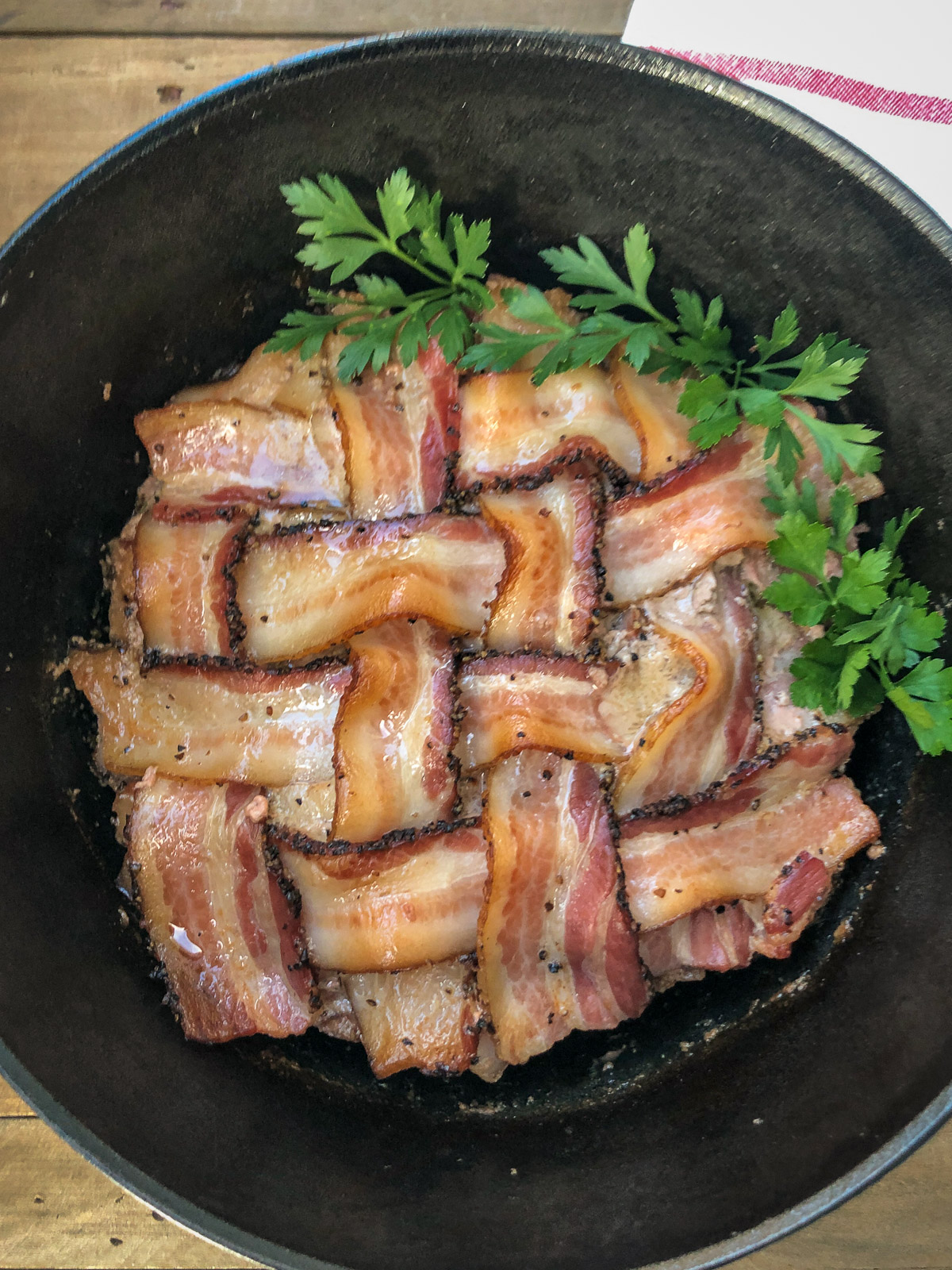 Overhead view of bacon wrapped meatloaf in a cast iron Dutch oven garnished with parsley