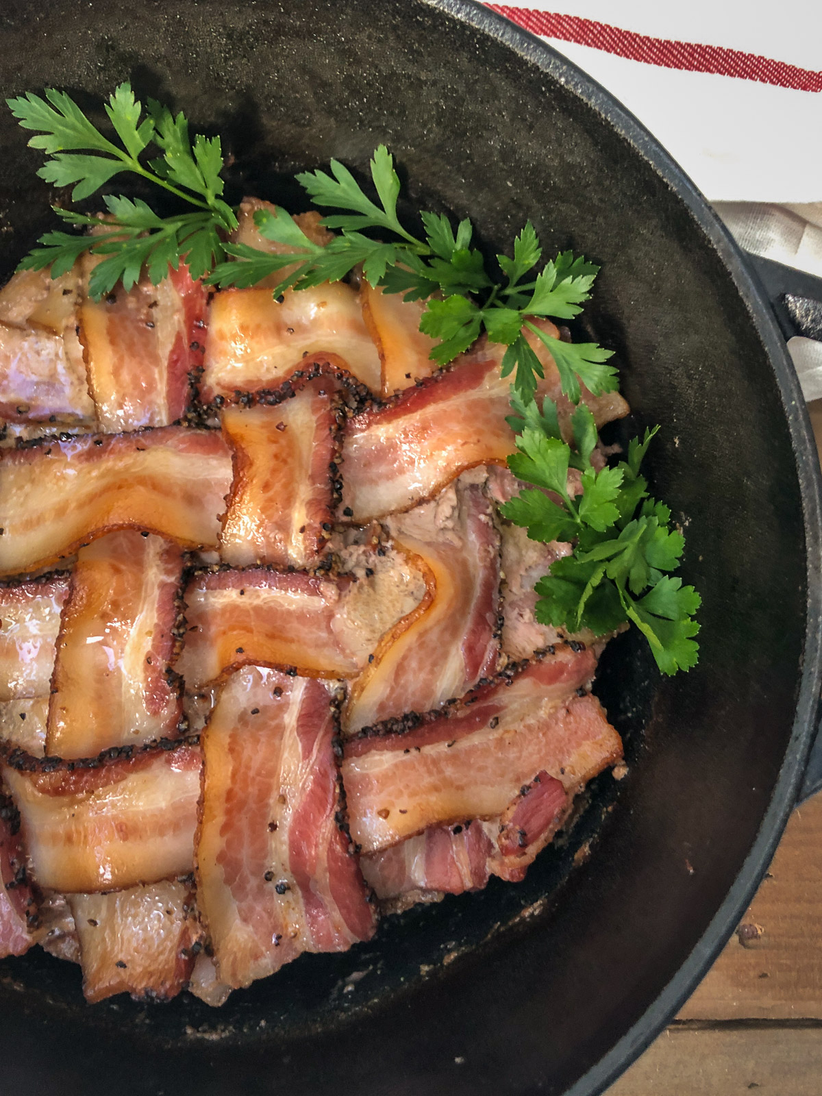 Close-up of bacon wrapped meatloaf in a Dutch oven showing the crispy bacon lattice weave