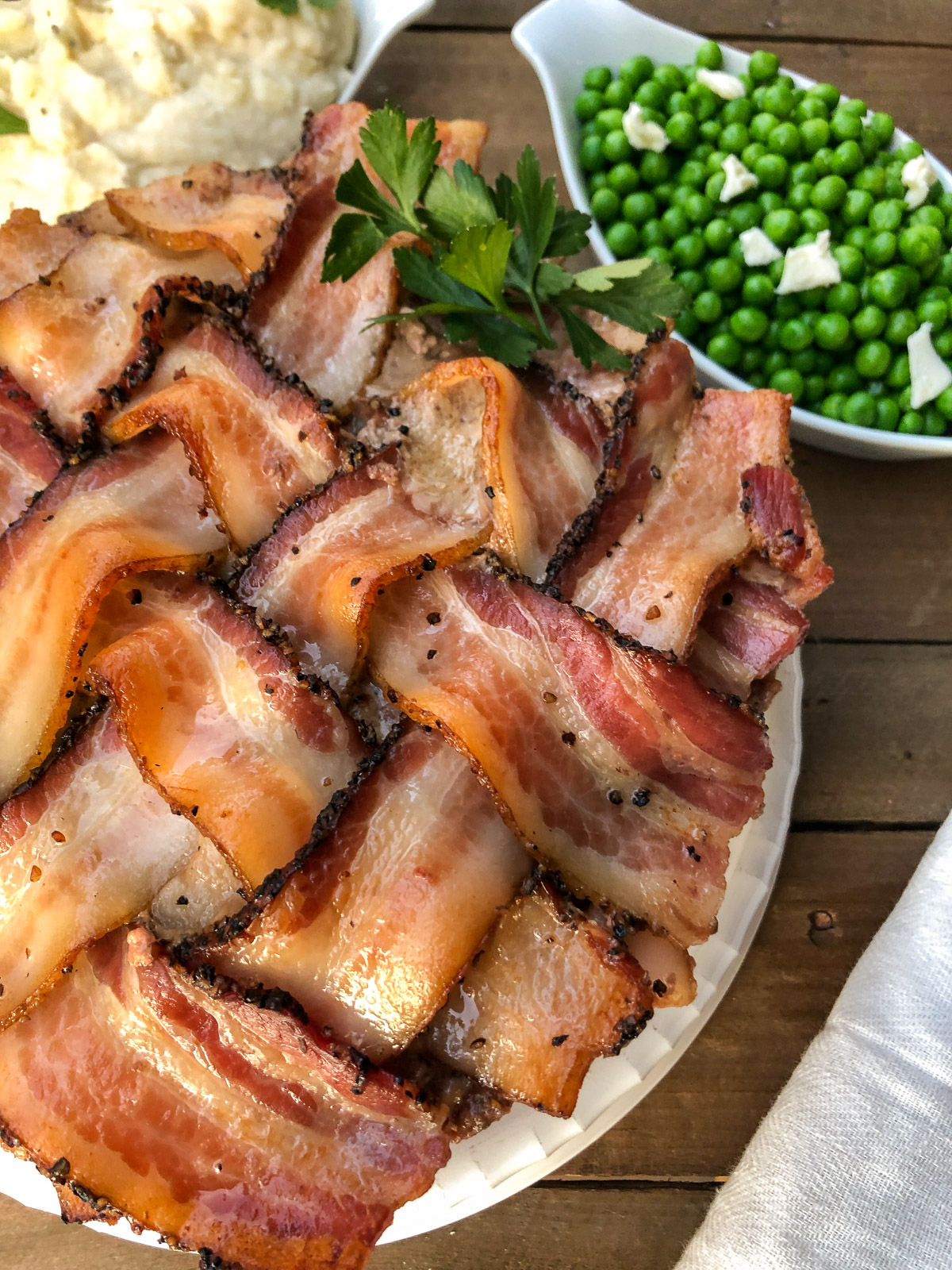 Close-up of sliced bacon wrapped meatloaf on a platter with side dishes