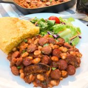 A serving of beanie weenies with cornbread and green salad.