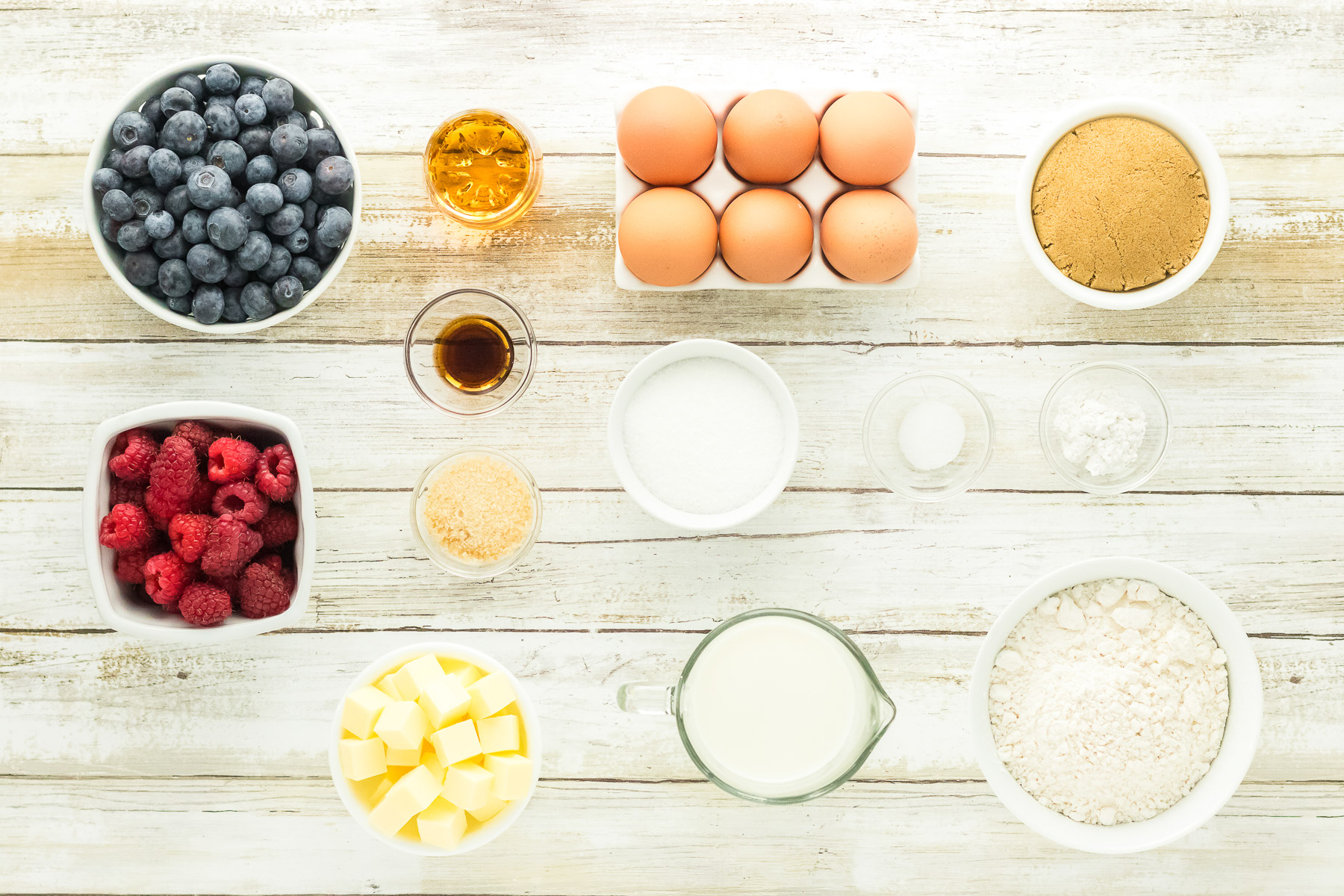 Ingredients for bourbon berry brown sugar cake including blueberries raspberries brown sugar eggs bourbon vanilla butter milk and flour