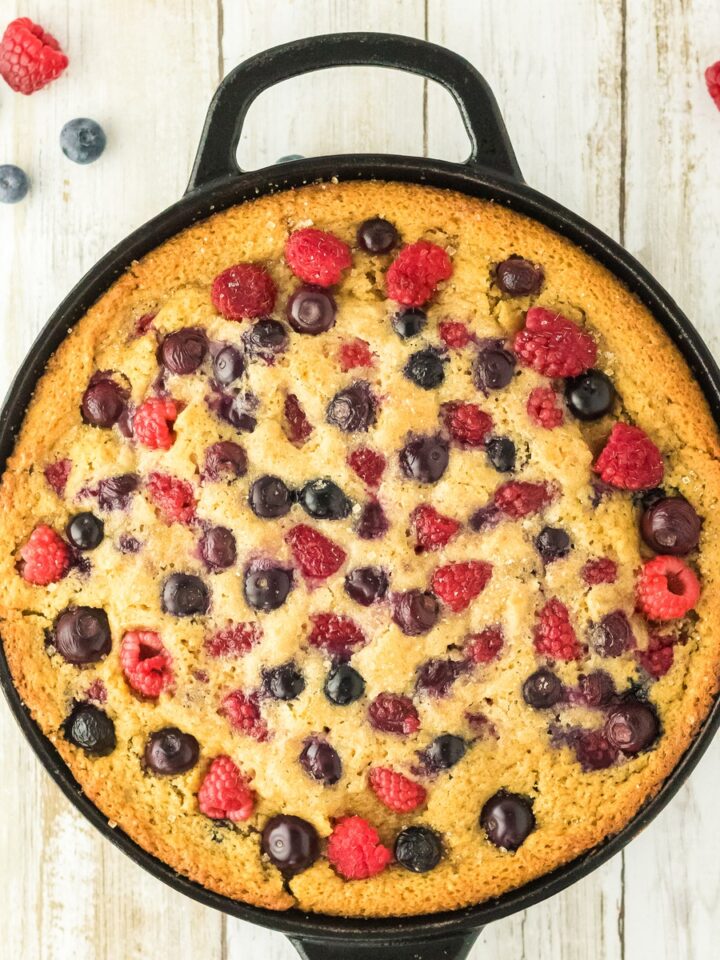 Bourbon berry brown sugar cake baked in a cast iron skillet with raspberries and blueberries