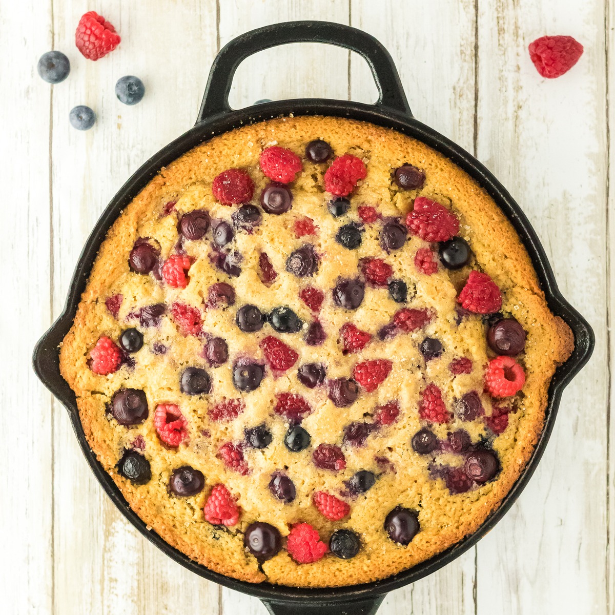 Bourbon berry brown sugar cake baked in a cast iron skillet with raspberries and blueberries