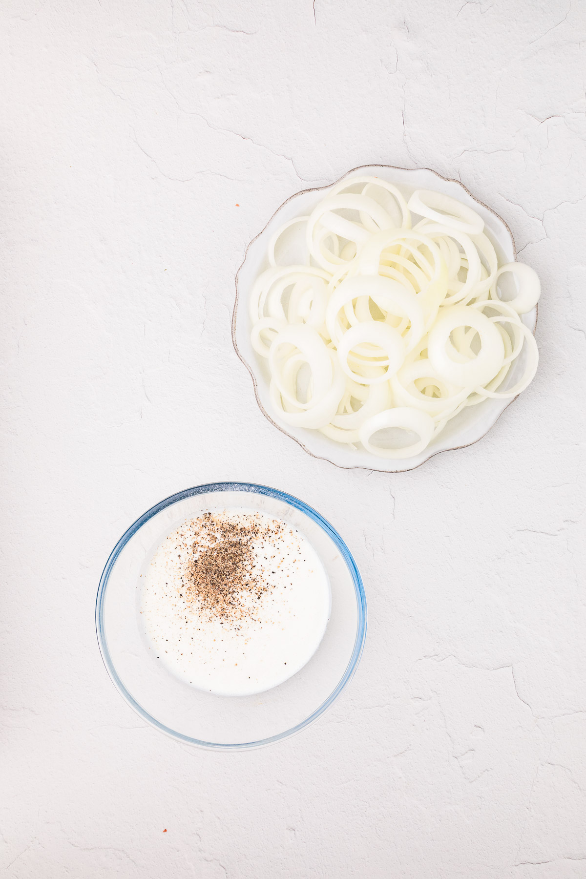 Sliced onions soaking in a bowl of buttermilk