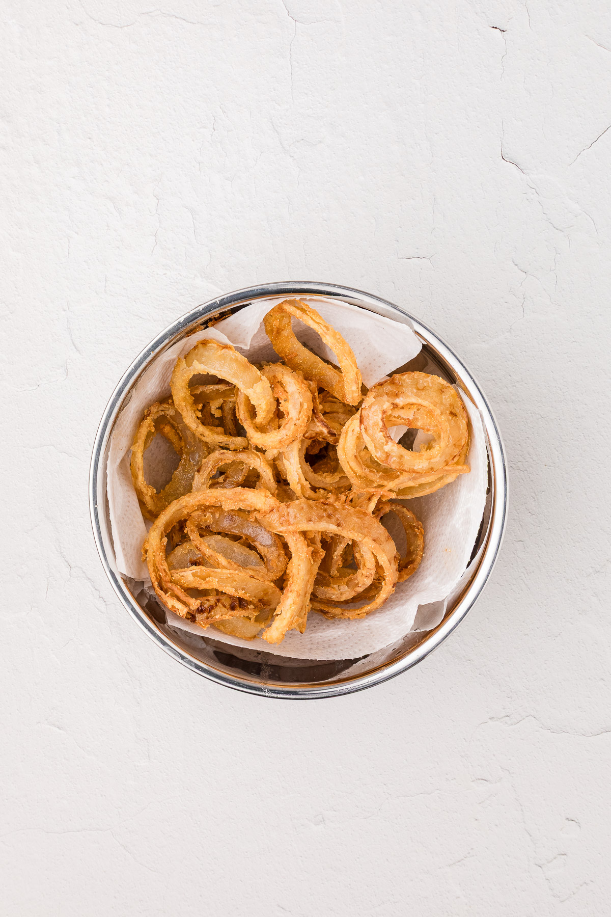 Golden fried rings draining on a wire rack over a sheet pan