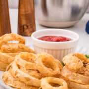 Crispy buttermilk onion rings on a white plate with ketchup