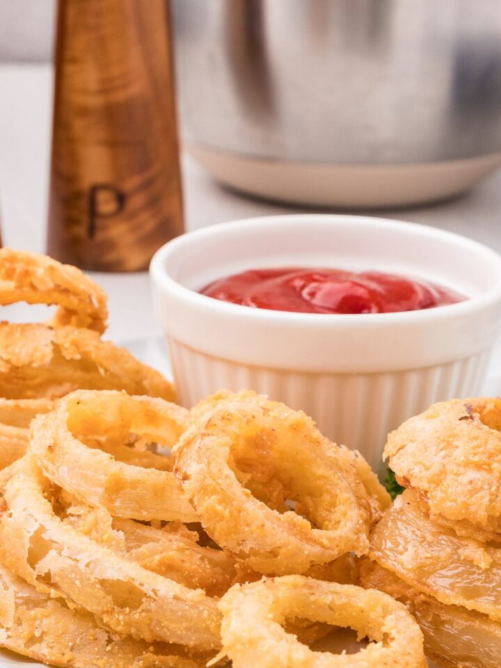 Crispy buttermilk onion rings on a white plate with ketchup