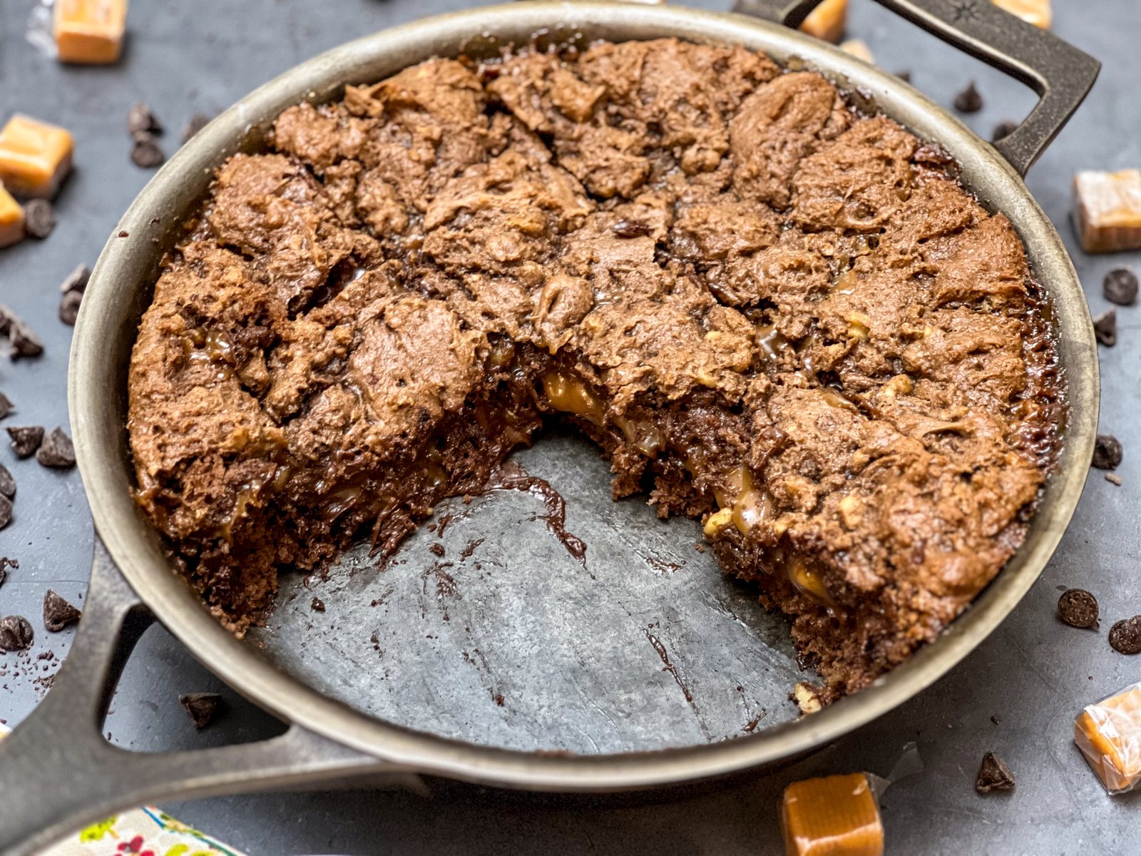 A slice of caramel brownie removed from the skillet showing the gooey caramel center.