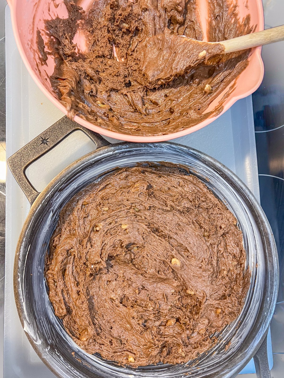 Half of the brownie batter spread into a cast iron skillet.