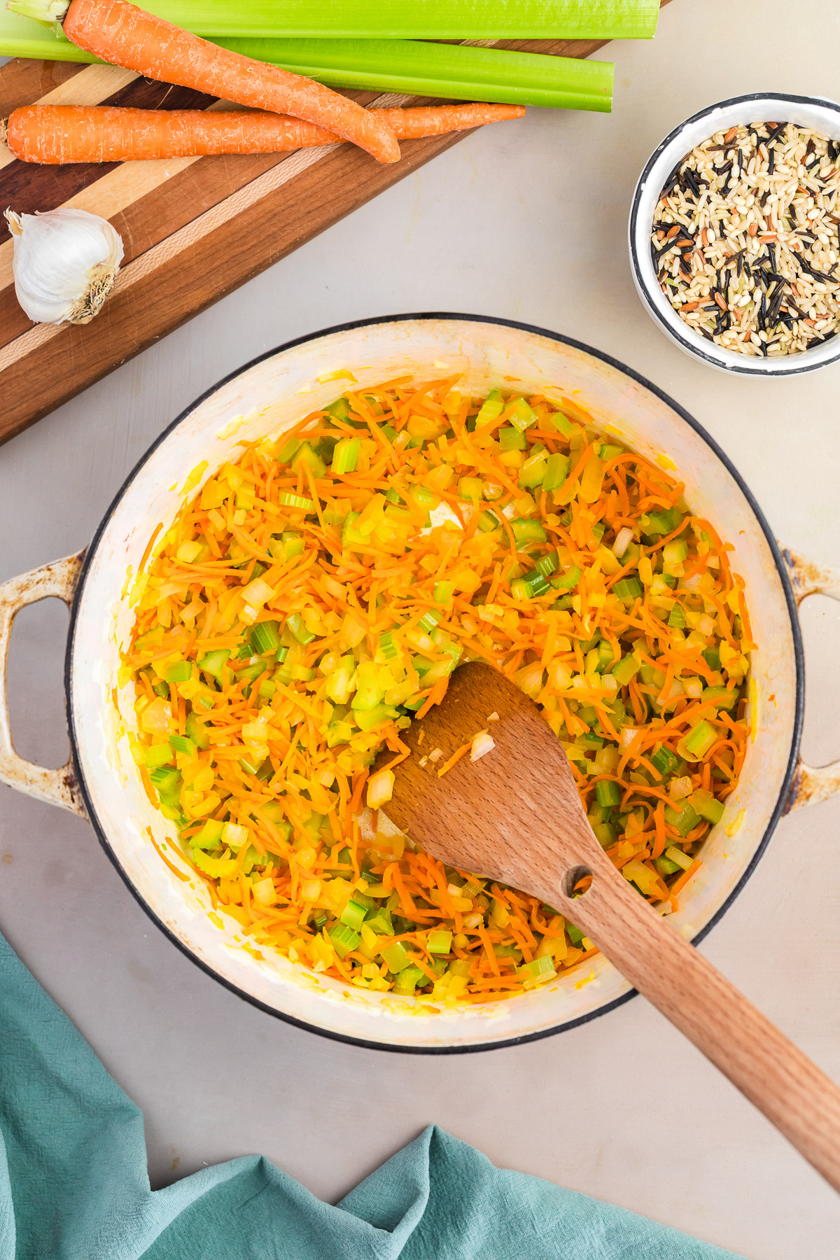 Sauteing diced onion, shredded carrots, and celery in a dutch oven for chicken wild rice soup