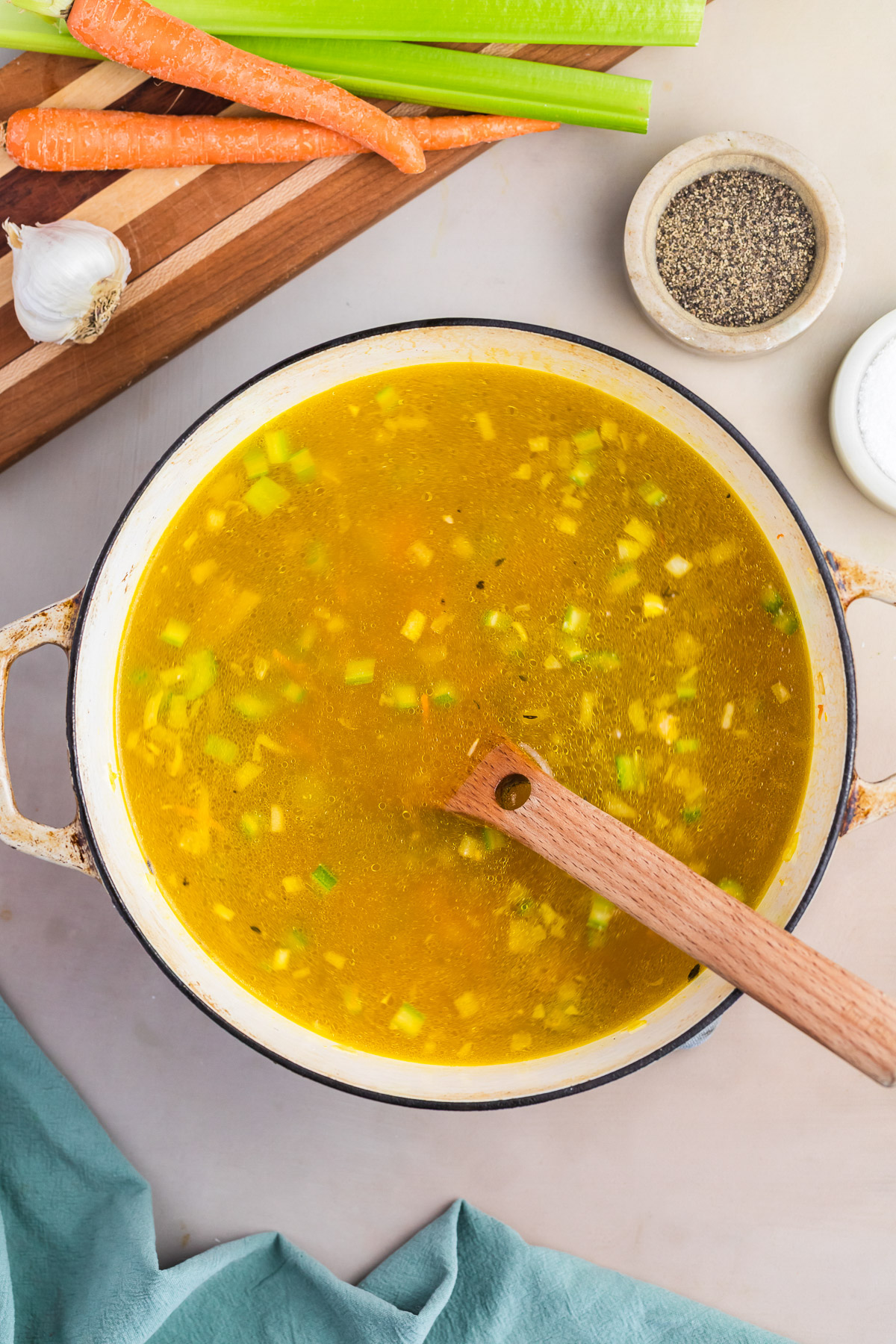 Chicken broth poured over wild rice and vegetables simmering in a dutch oven