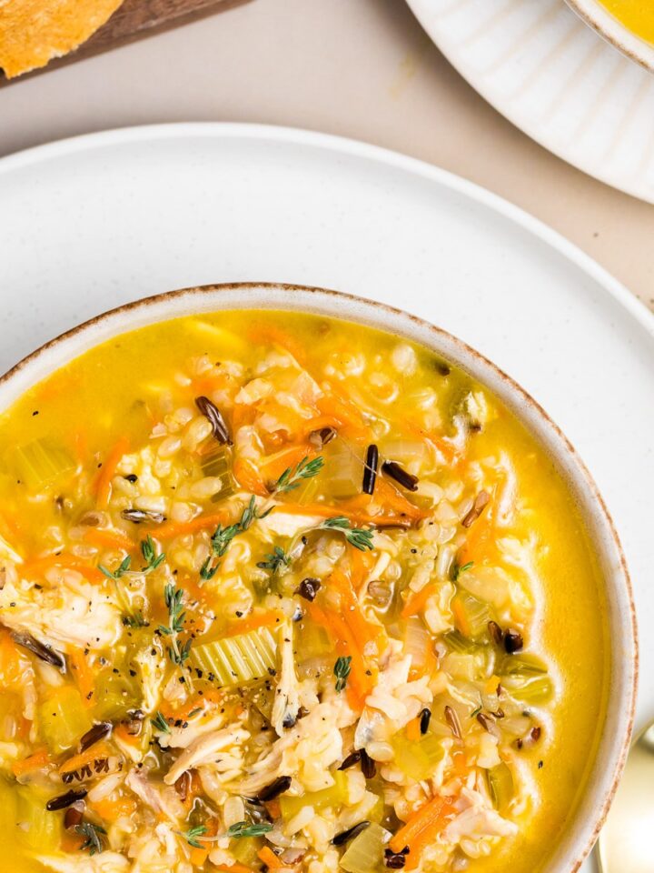Bowl of chicken wild rice soup with shredded chicken, wild rice, carrots, and fresh thyme