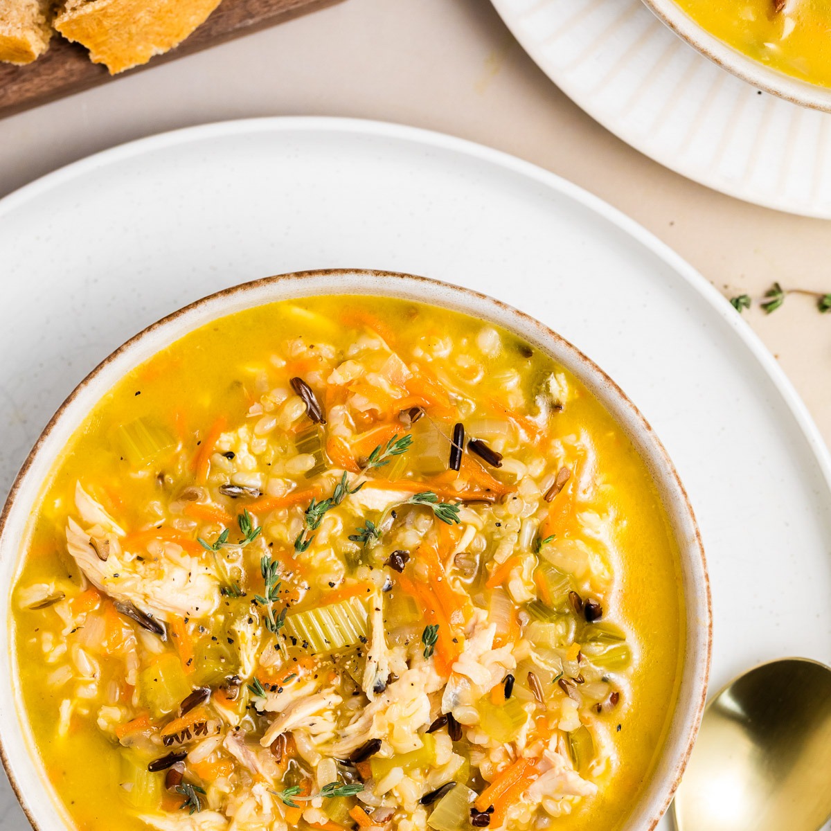 Bowl of chicken wild rice soup with shredded chicken, wild rice, carrots, and fresh thyme