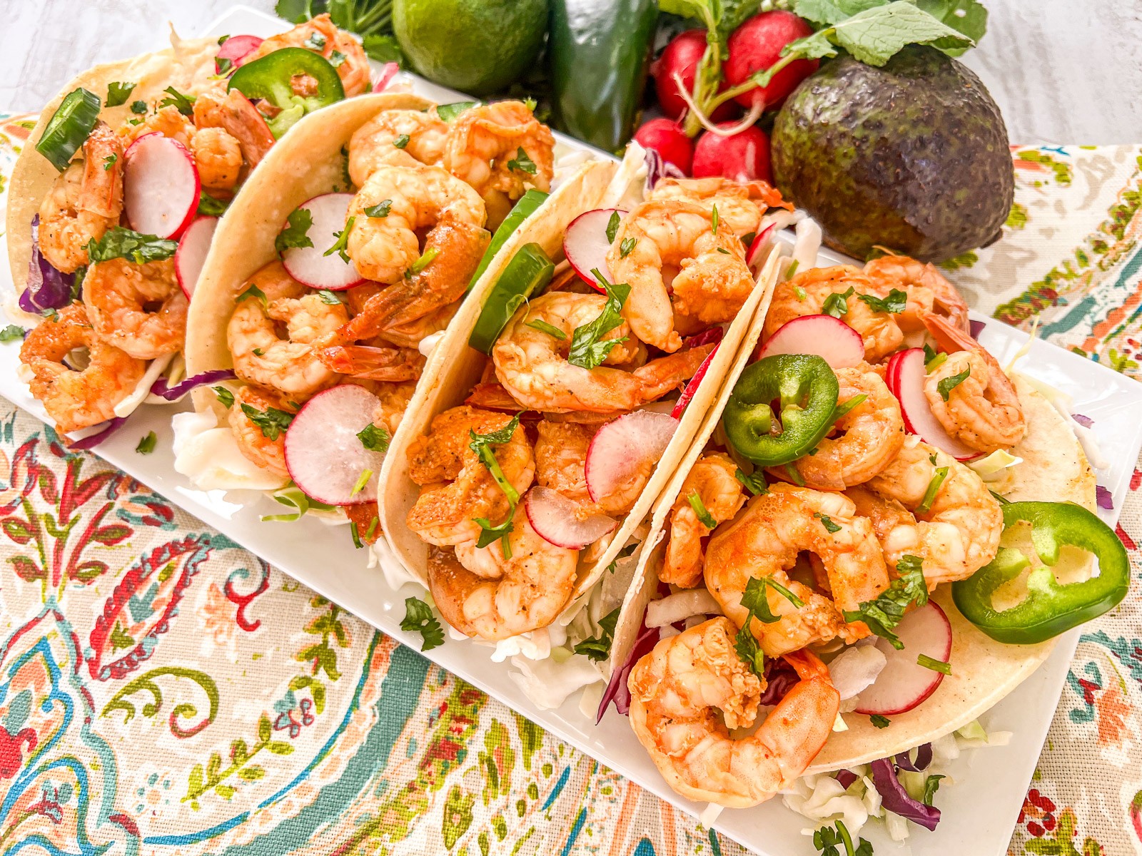 Chili lime shrimp on a plate with fresh lime wedges and chopped cilantro.