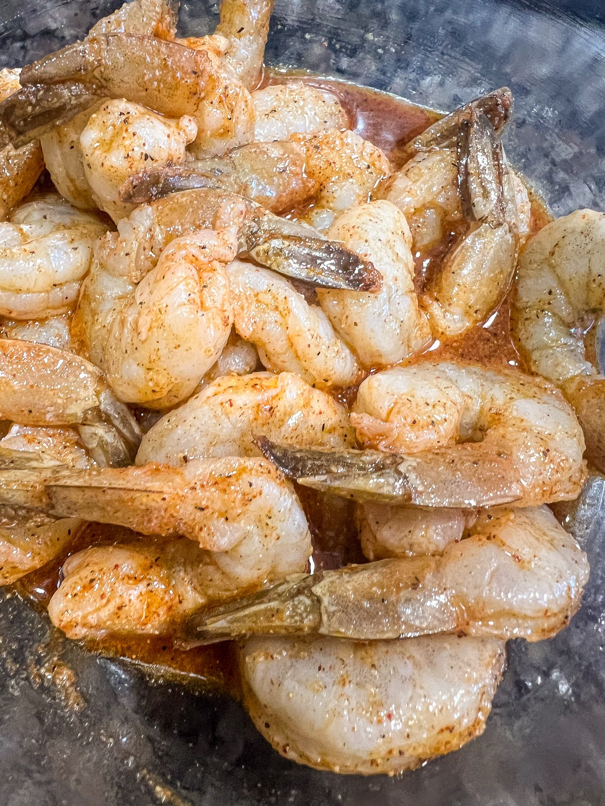 Raw shrimp tossed in chili lime marinade with visible chili powder and lime juice coating