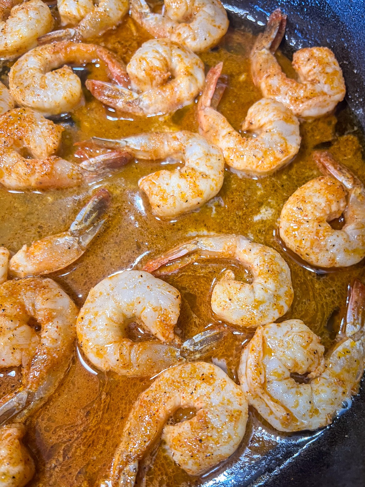 Shrimp being cooked in a cast iron skillet.
