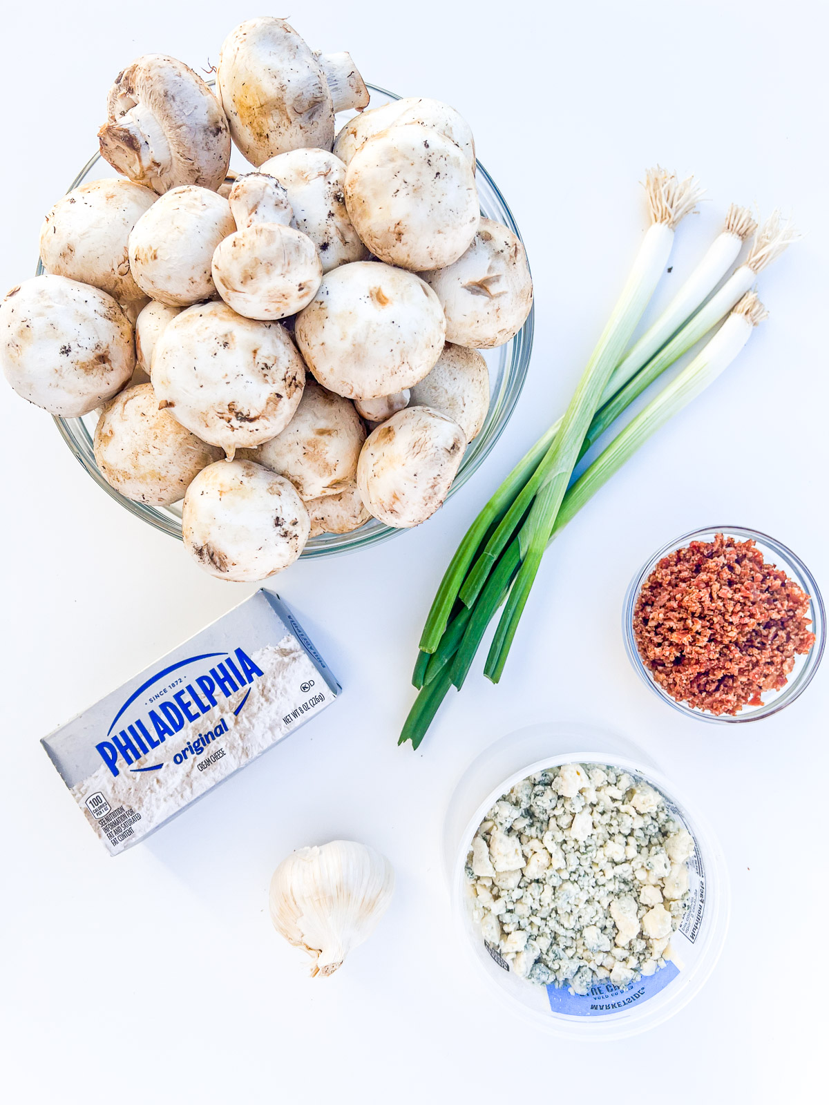 Ingredients for camp oven cream cheese stuffed mushrooms including cream cheese, mushrooms, garlic, blue cheese, bacon, and green onions.