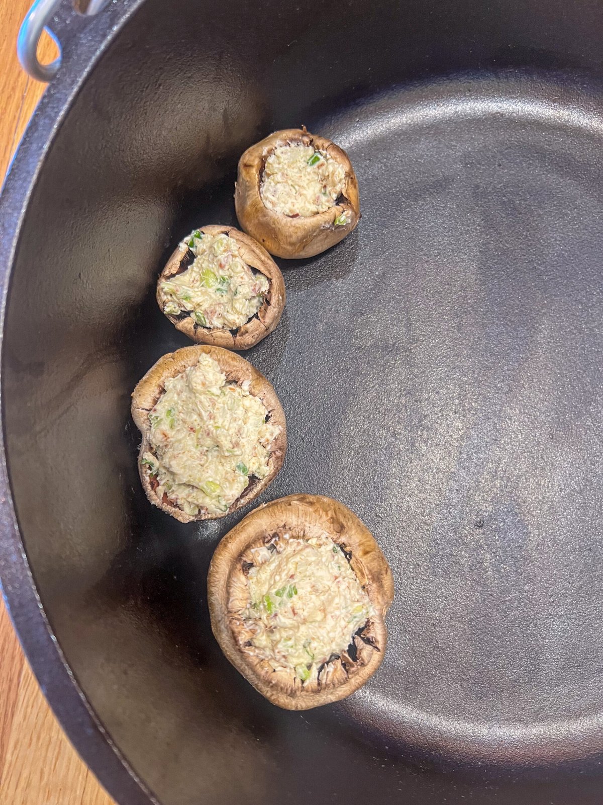 Stuffed mushrooms arranged in a 12 inch camp Dutch oven over coals at a campsite.