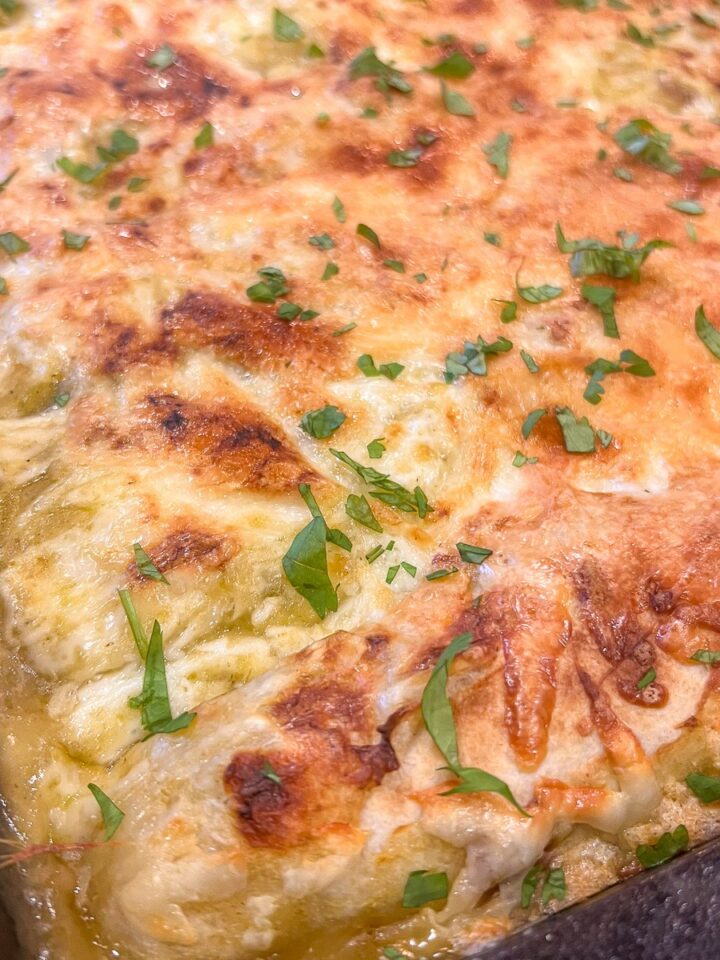 Creamy green chile chicken enchiladas baked in a cast iron pan.