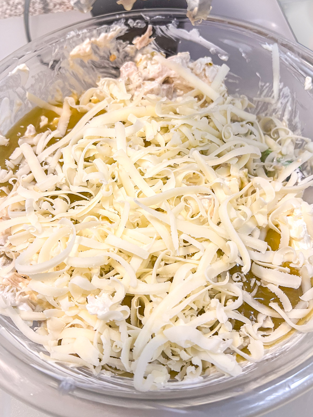 Adding green enchilada sauce and shredded cheese to the chicken mixture