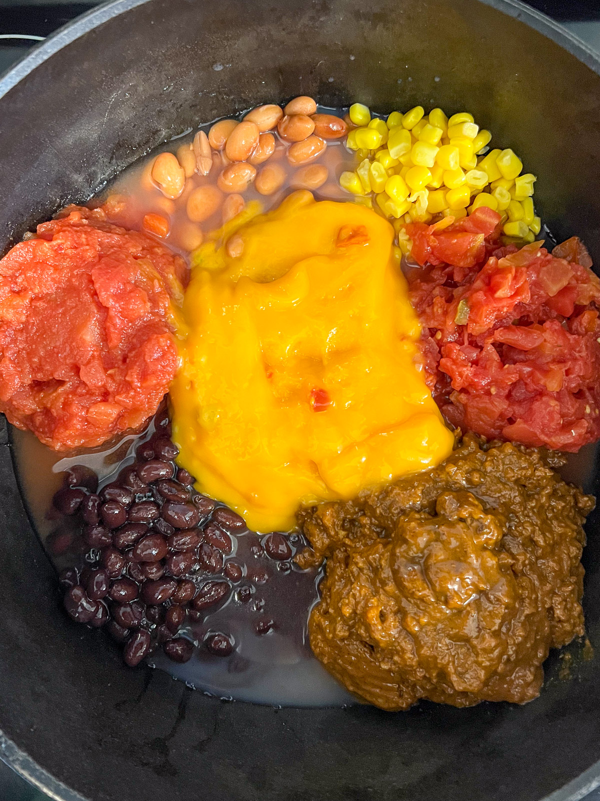 Seven cans of ingredients being added to a dutch oven for 7 can soup