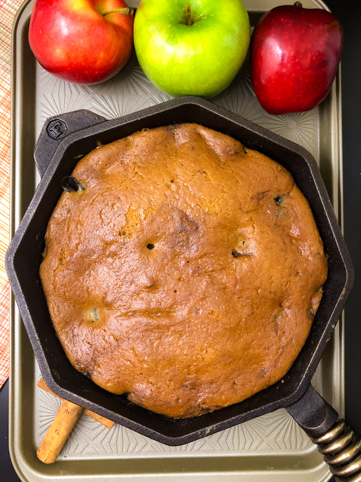 Golden brown baked dutch oven apple cake in a black cast iron skillet fresh from the oven