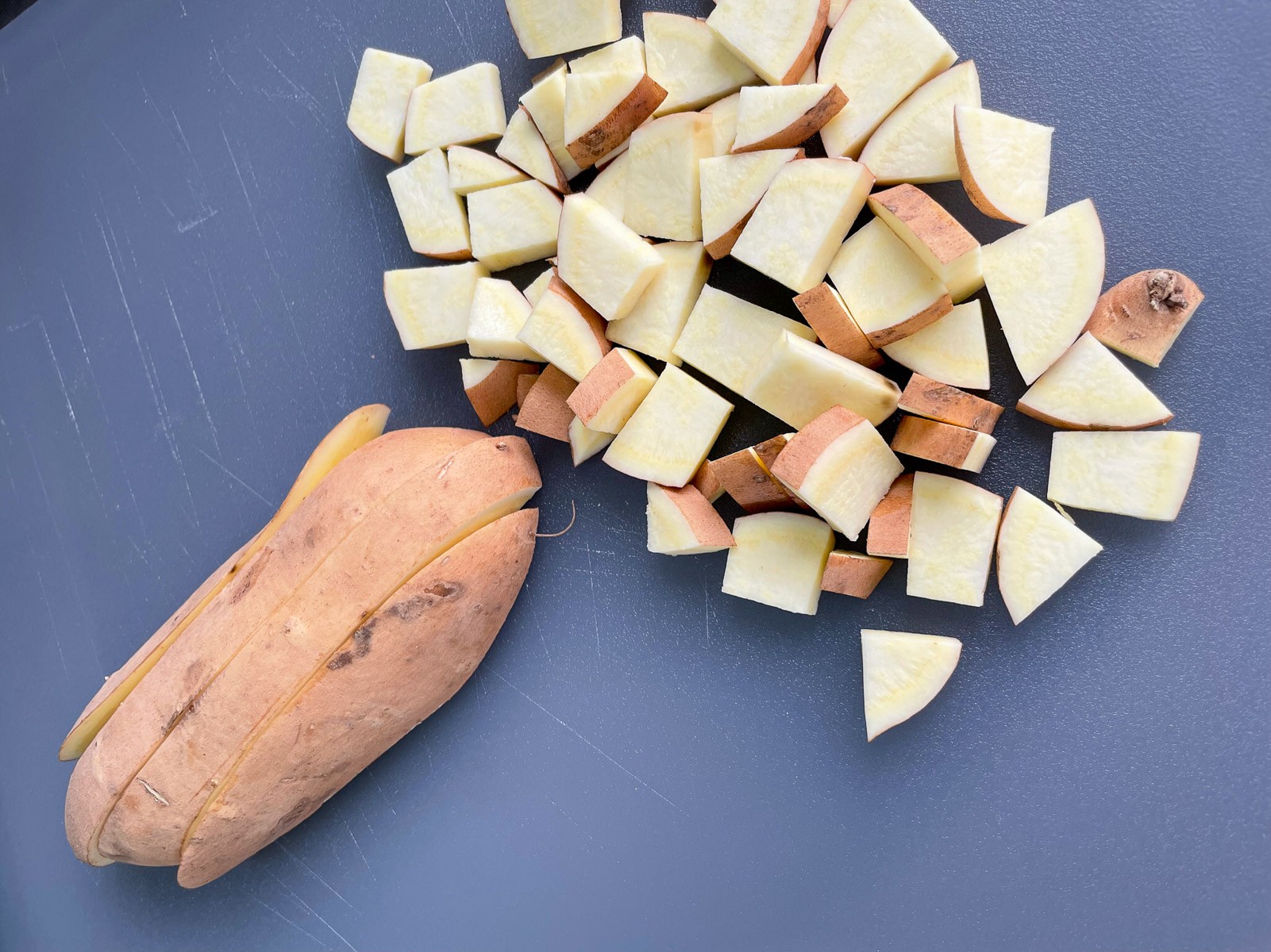 Diced sweet potatoes on a cutting board for Dutch oven mountain man breakfast.