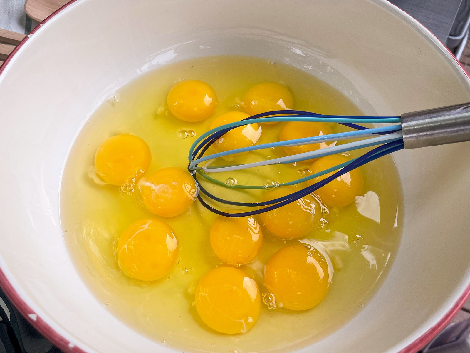 Eggs cracked into a bowl with a whisk for mountain man breakfast.
