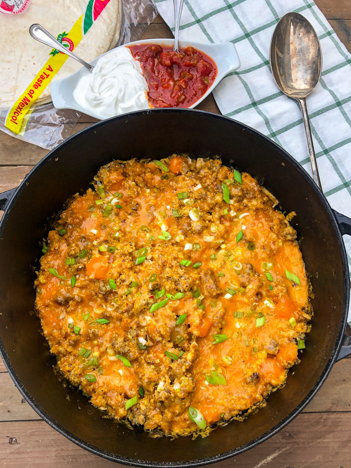 Dutch oven mountain man breakfast with melted cheddar cheese and green onions, ready to serve.