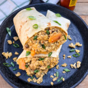 Mountain man breakfast burrito on a cast iron skillet with green onions and hot sauce.